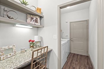 A hallway with a built-in desk with wall shelves and under-shelf light, and a laundry room with included washer and dryer.